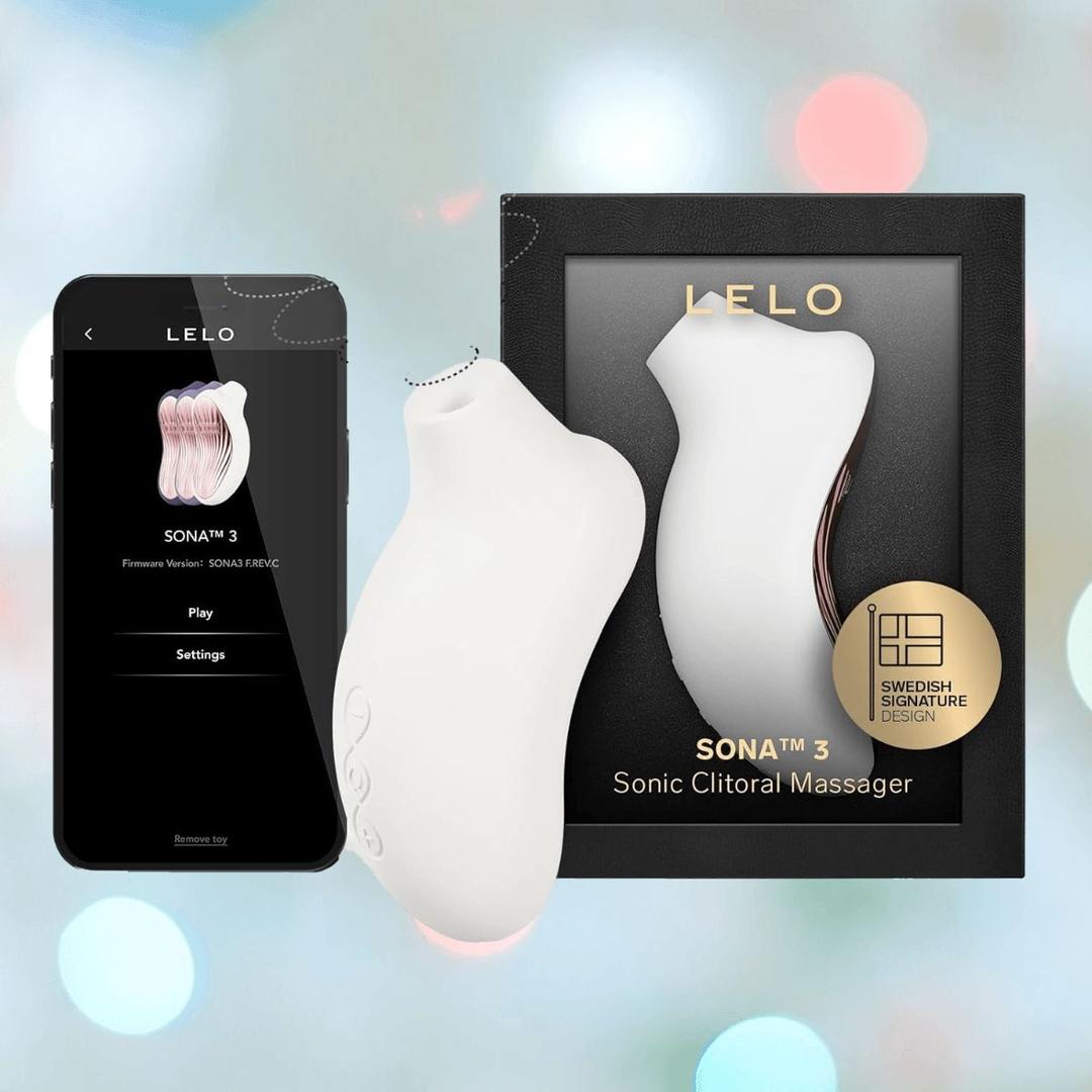A LELO Sona 3 - Cream by LELO is displayed beside its black box and a smartphone featuring the LELO app, set against a softly blurred background with blue and pink lights. A LELO Sona 3 - Cream by LELO is displayed beside its black box and a smartphone featuring the LELO app, set against a softly blurred background with blue and pink lights.