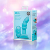 A blue box of the b-Vibe Remote Rimming P-Spot Plug by B-Vibe rests on a purple and pink blurred background, packaging displaying the plug and remote with highlighted features. A blue box of the b-Vibe Remote Rimming P-Spot Plug by B-Vibe rests on a purple and pink blurred background, packaging displaying the plug and remote with highlighted features.