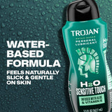 A 5.5oz bottle of Trojan H2O Sensitive Touch with Aloe Lubricant by Trojan, shown against a backdrop of water droplets with text highlighting its gentle, slick formula infused with aloe and vitamin E—an ideal choice for sensitive skin.