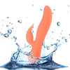 The BMS Swan The Blossom Rabbit Vibrator in Coral, a waterproof silicone rabbit-style toy with a curved design and smaller extension, is shown splashing into water against a white background.