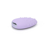 The Je Joue Mimi Deux Pebble Vibrator in Lilac is a compact, pebble-shaped object featuring a dual-texture design with both smooth and textured surfaces. Its lustrous metallic accents on one side elegantly contrast against a pure white background, exuding sophistication in every detail.