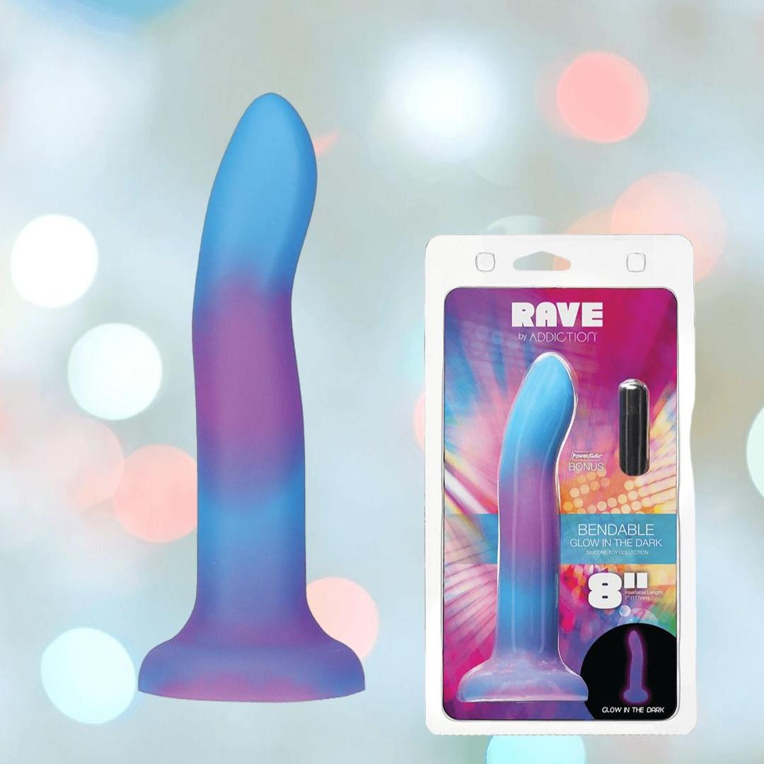 The Addiction Rave Glow-in-the-Dark Bendable Vibrating Dong by BMS in blue and purple is shown with its packaging, highlighting its 8-inch length, strong suction base, and glowing feature against a colorful background.