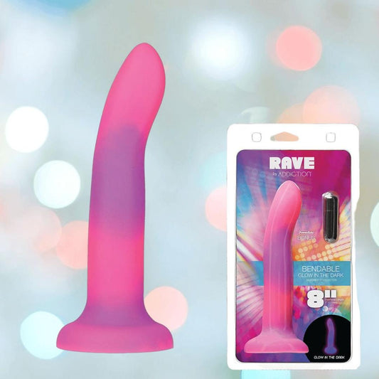 The Addiction Rave Glow-in-the-Dark Bendable Vibrating Dong by BMS is shown in pink and purple alongside its colorful packaging featuring product details, a strong suction base, and an 8-inch size. 1080