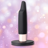The Aspen 15-Function Flickering Tip Vibrator by Maia Toys is a compact pleasure companion in black and rose gold, featuring a rounded base and tapered top, displayed against a blurred pastel background with soft circular light spots.