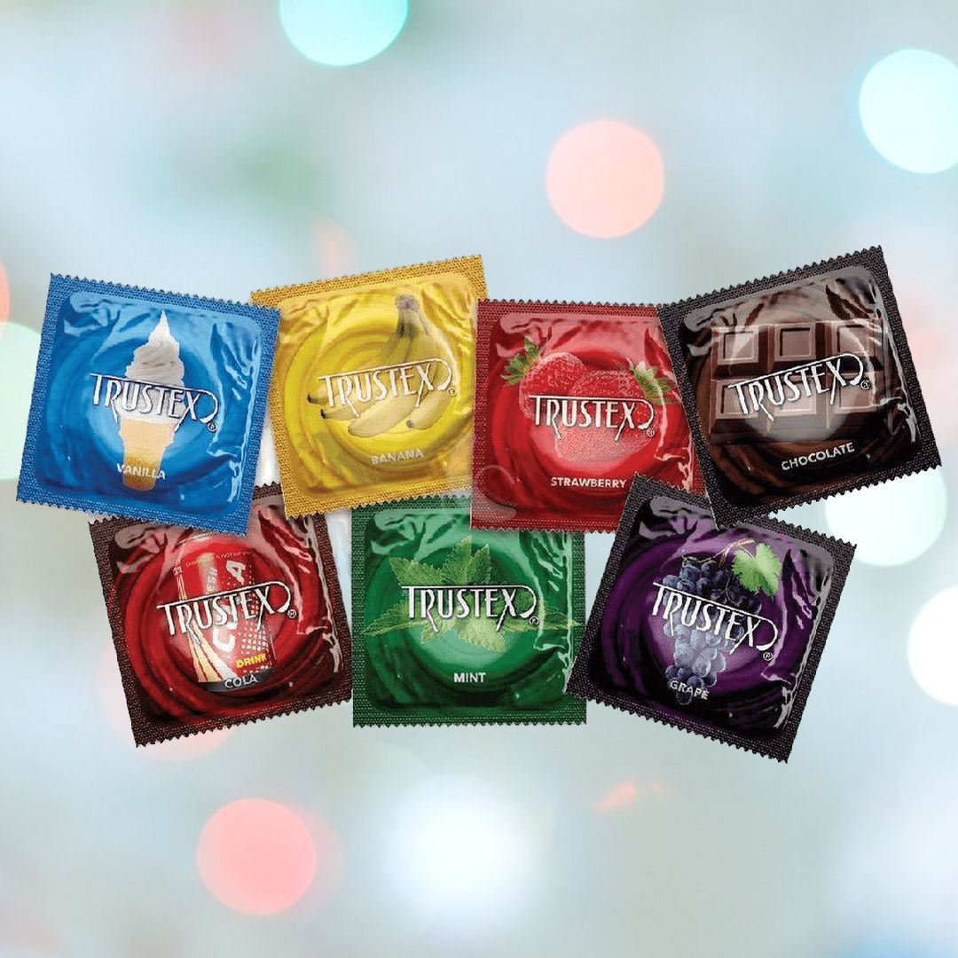 A set of seven vibrant Assorted Flavored Trustex Condoms 🍓 🍌 🍫 is arranged against a blurred backdrop, emphasizing the delightful range of flavors. This collection features options like vanilla, banana, strawberry, chocolate, mint, grape, and cola. Every Trustex condom is FDA-approved for safety and reliability.