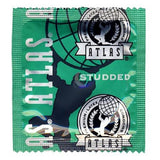 A sealed green foil packet from Condomania contains a free sample of Atlas Studded Condoms (limit 1), featuring textured latex condoms for enhanced pleasure and branded with Atlas artwork and logos in black and white.