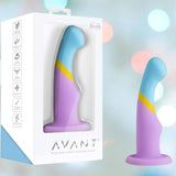 The Avant D14 Heart of Gold, a pastel artisanal toy in blue, yellow, and purple platinum-cured silicone, is shown inside and outside its white Avant box featuring icons on a softly blurred background.