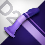 A curved Avant D2 6" Non-Porous Silicone Dildo in shades of purple and lavender, featuring a flared suction cup base, rests on a diagonally split background of gray and dark purple with the text "D2" partially visible behind it.