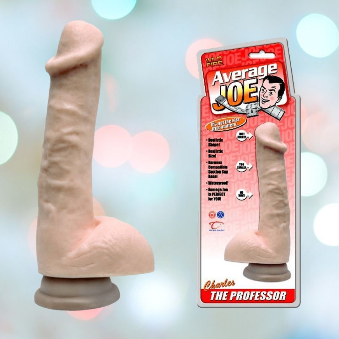 The "Average Joe The Professor Charles Realistic Dildo with Suction Cup" by Average Joe is displayed unboxed, showcasing its lifelike design and harness-compatible suction cup base. The packaging highlights its phthalate-free material and average size, set against a softly blurred pastel background.