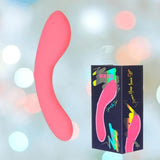 The BMS The Mini Swan Wand Glow in the Dark - Pink by bms is shown next to its black box, which displays the massager and colorful details. The soft background features blurred pastel bokeh lights.