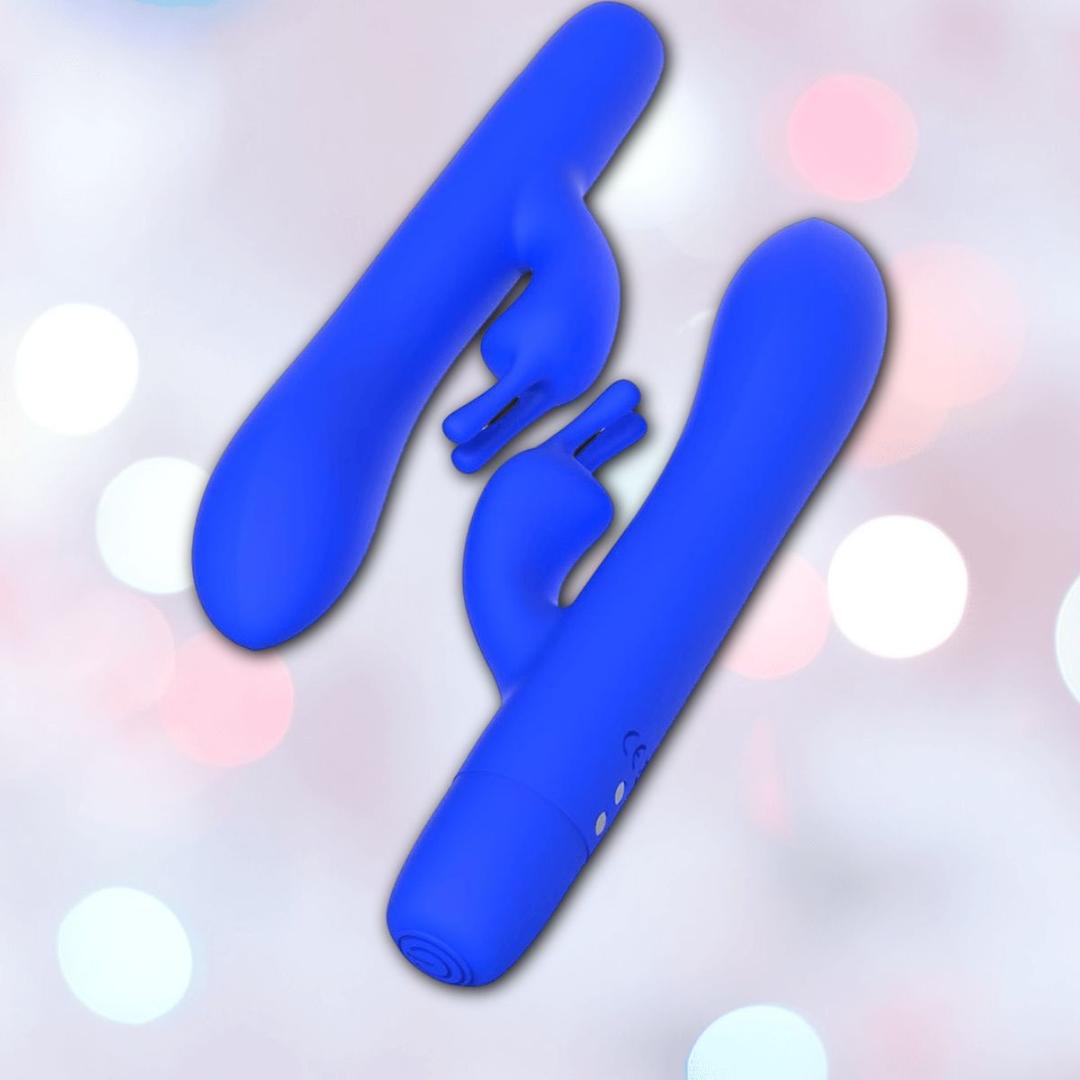 Two B Swish Limited Edition Bwild Bunny vibrators in Pacific Blue (Dented Box) are displayed with their curved shafts and silicone clitoral stimulator arms against a blurred pastel bokeh background.