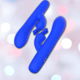 Two B Swish Limited Edition Bwild Bunny vibrators in Pacific Blue (Dented Box) are displayed with their curved shafts and silicone clitoral stimulator arms against a blurred pastel bokeh background.