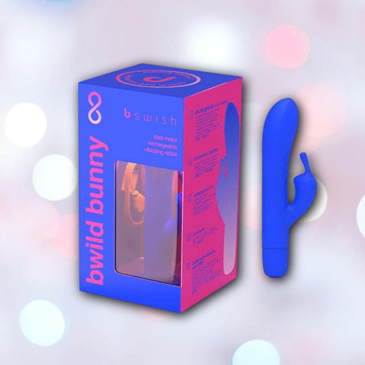 A B Swish Limited Edition Bwild Bunny - Pacific Blue (Dented Box) silicone clitoral stimulator stands upright beside its branded packaging, set against a softly blurred background with pastel circles. 1080
