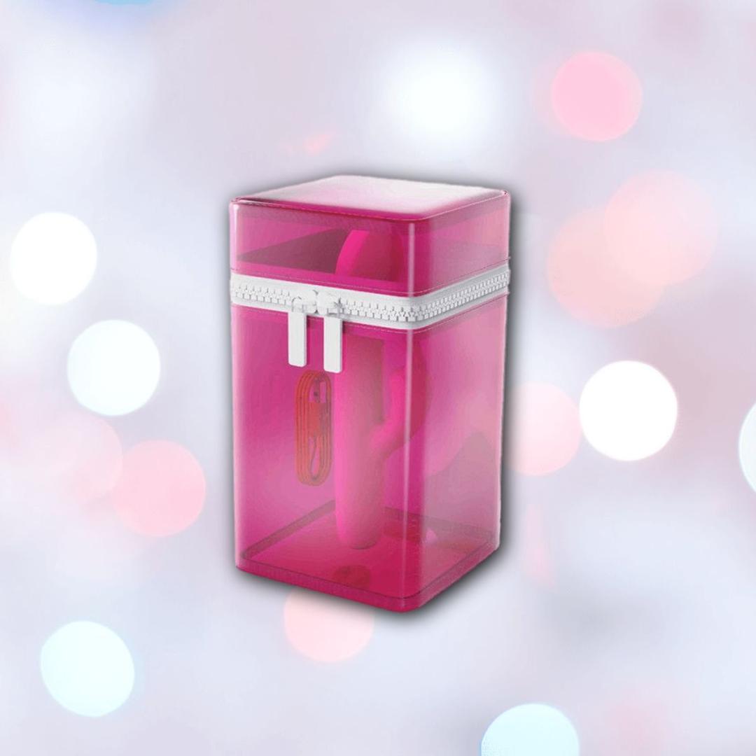 A translucent pink zippered container stands upright, revealing the B Swish Limited Edition Bwild Infinite Bunny - Sunset Pink vibrator inside, set against a softly blurred pastel background.