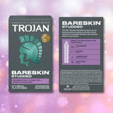 Two boxes of Trojan Studded Bareskin Condoms by Trojan are shown against a pink and purple bokeh background. The front box features the brand logo and product name, while the back box highlights key features of these thin, textured condoms, including their enhanced shape and added lubricant.