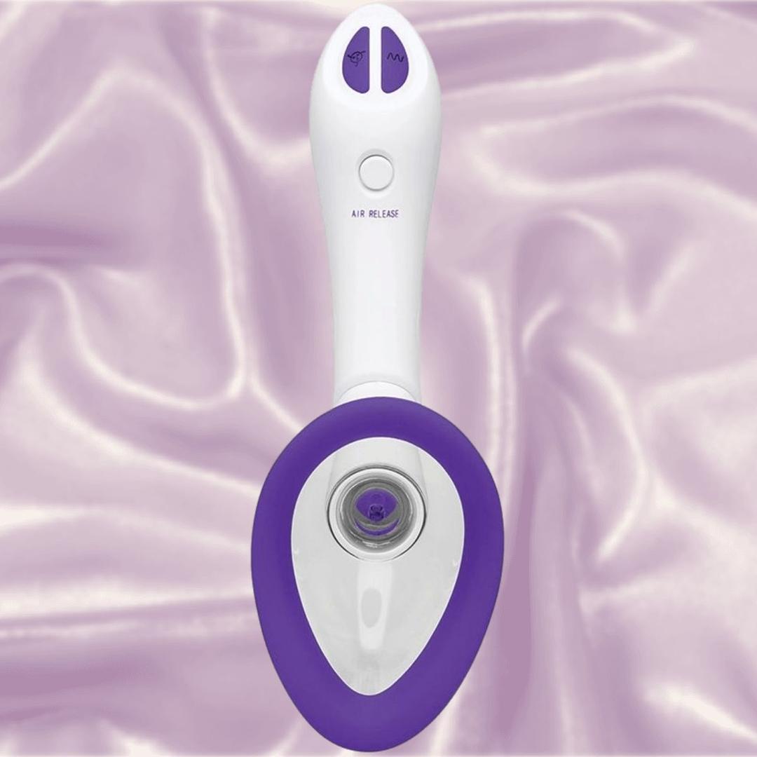 The Doc Johnson Bloom Rechargeable Intimate Body Pump - Purple is a white and purple handheld device with interchangeable cups, two buttons, and a central circular opening, shown on silky, light purple fabric.