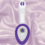 The Doc Johnson Bloom Rechargeable Intimate Body Pump - Purple is a white and purple handheld device with interchangeable cups, two buttons, and a central circular opening, shown on silky, light purple fabric.