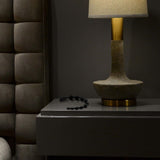 In a dimly lit room, a textured bedside lamp sits on a sleek dark nightstand with Blush Novelties' Anal Adventures Platinum Ultrasilk Silicone 10 Beads nearby. The cushioned dark wall panels enhance the cozy atmosphere, perfect for intimate moments.