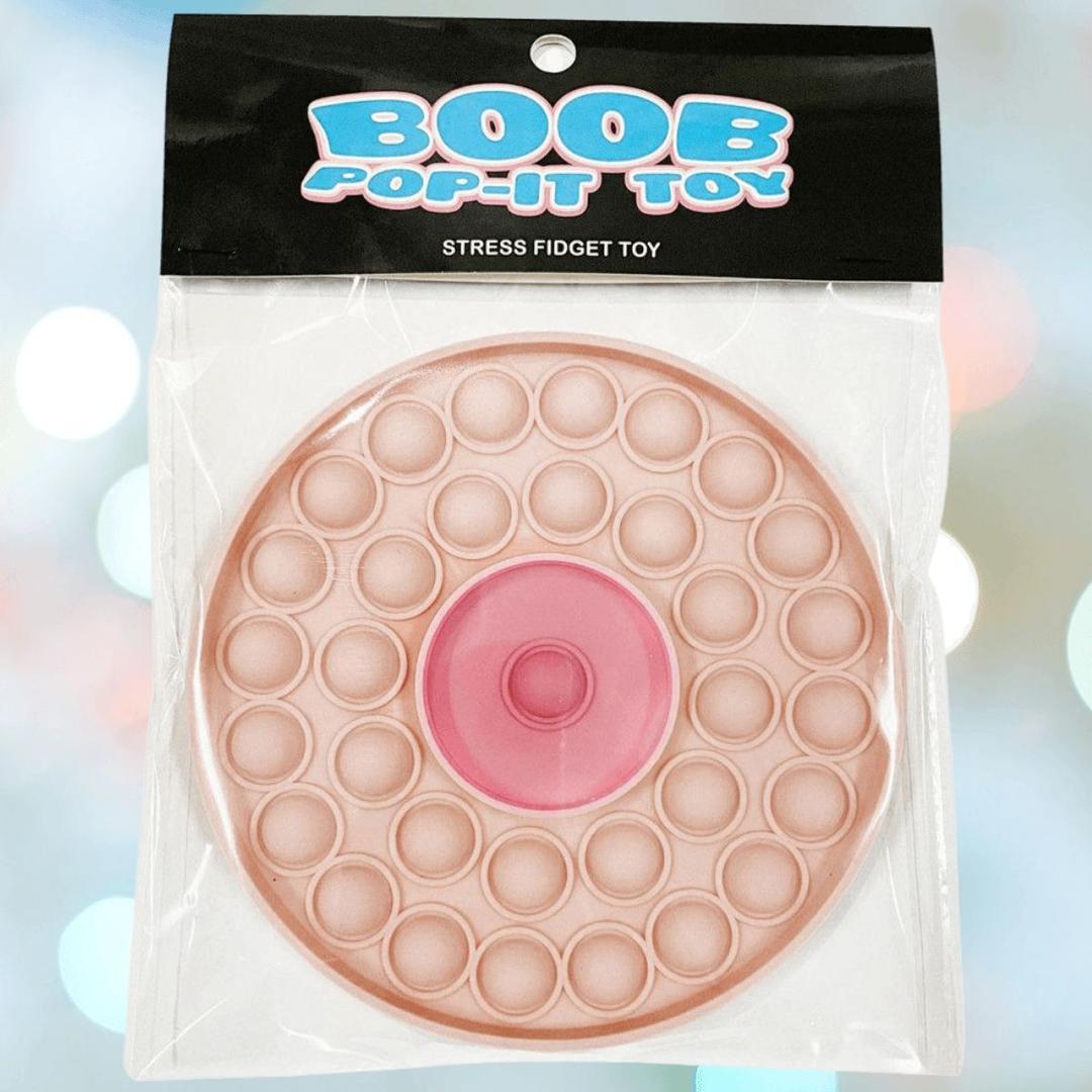 The Kheper Games Boob Pop-It Toy is a round, flesh-toned fidget toy with a pink center, packaged in a clear bag labeled "BOOB POP-IT TOY Stress Fidget Toy"—perfect for stress relief.