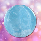 A circular, light blue, textured Fleshjack Boys Boomer Banks: Realistic Male Masturbator Cake Butt BIRTHDAY EDITION shaped like a gluteus on a pink and purple bokeh background.