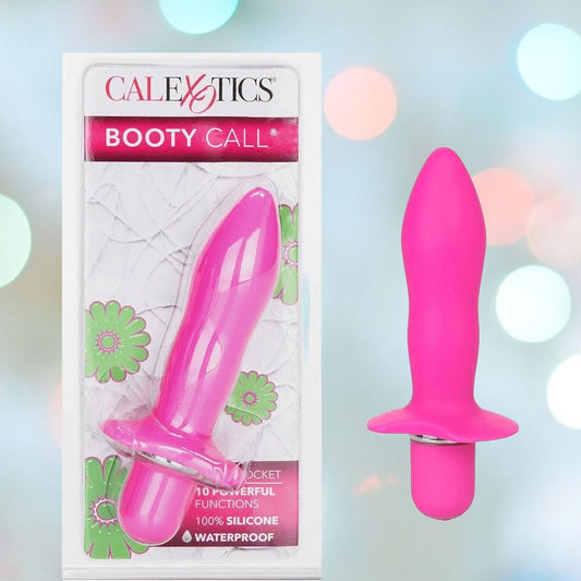 The Booty Call "Booty Rocket" Vibrating Anal Stimulator by CalExotics is displayed alongside its attractive floral-themed packaging. This boxed pink silicone personal massager, specifically designed for prostate stimulation, highlights its waterproof feature and various functions. The image is accentuated by soft focus lights in the background. 1080