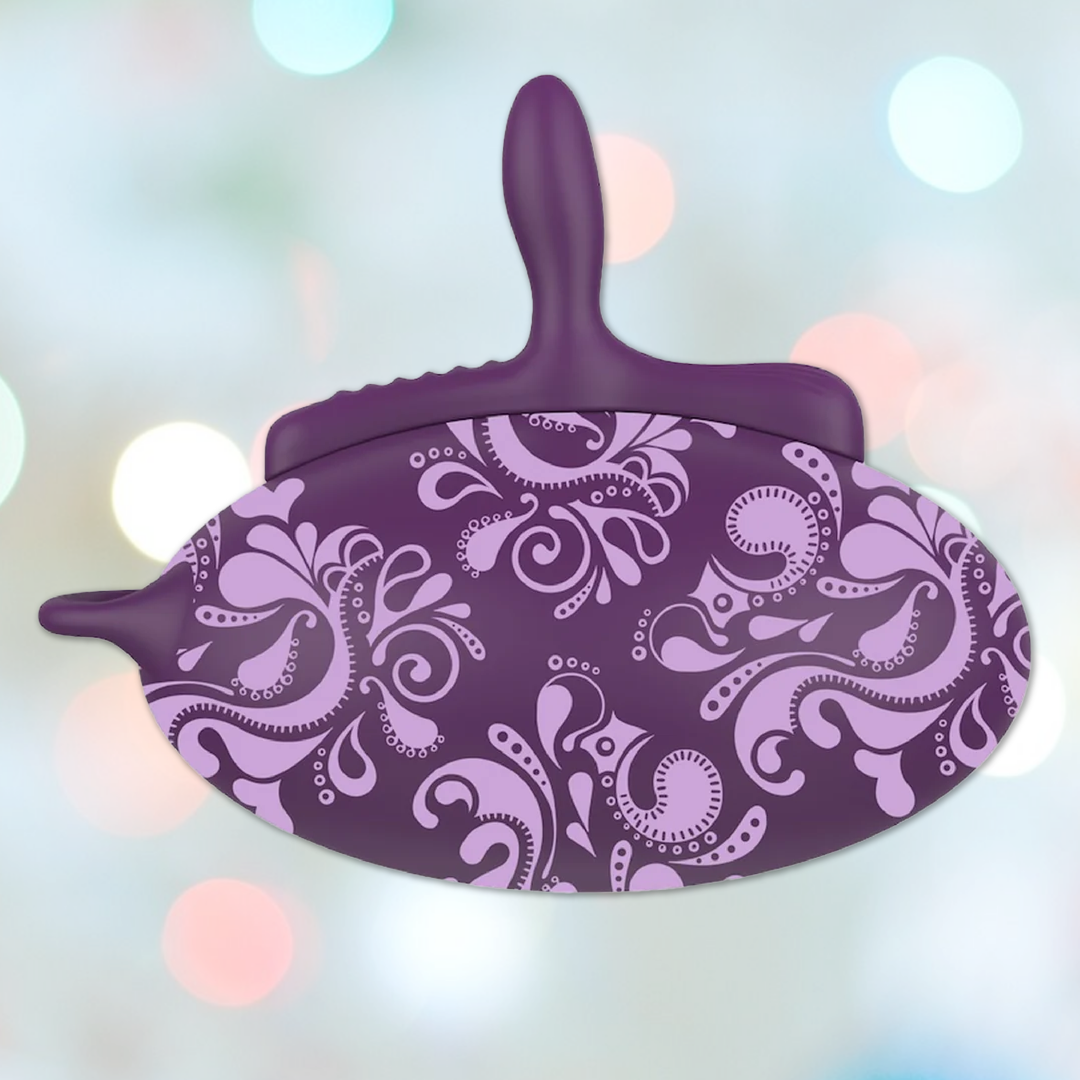 A purple sled features a handle and an intricate paisley design in lighter purple against a bokeh background. With its inflatable seat, the Bouncy Bliss offers ultimate snow fun.