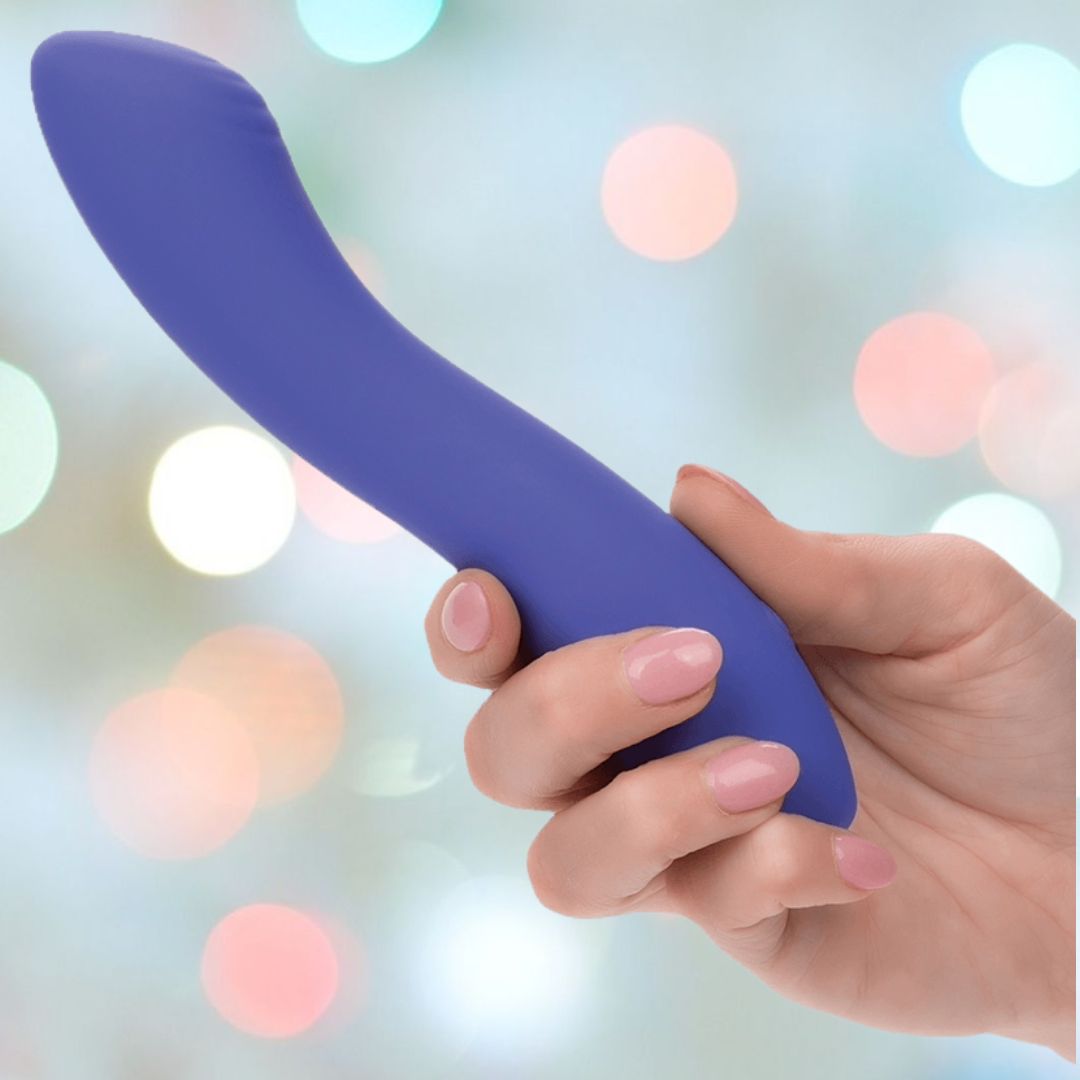 A hand holding a blue, curved CalExotics Connect Contoured "G" against a blurred background with multicolored lights.