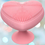 The CalExotics Posh Kiss Me Handheld Massager features a pink, heart-shaped design with textured pleasure nubbies and a suction base, shown against a soft, blurred background.