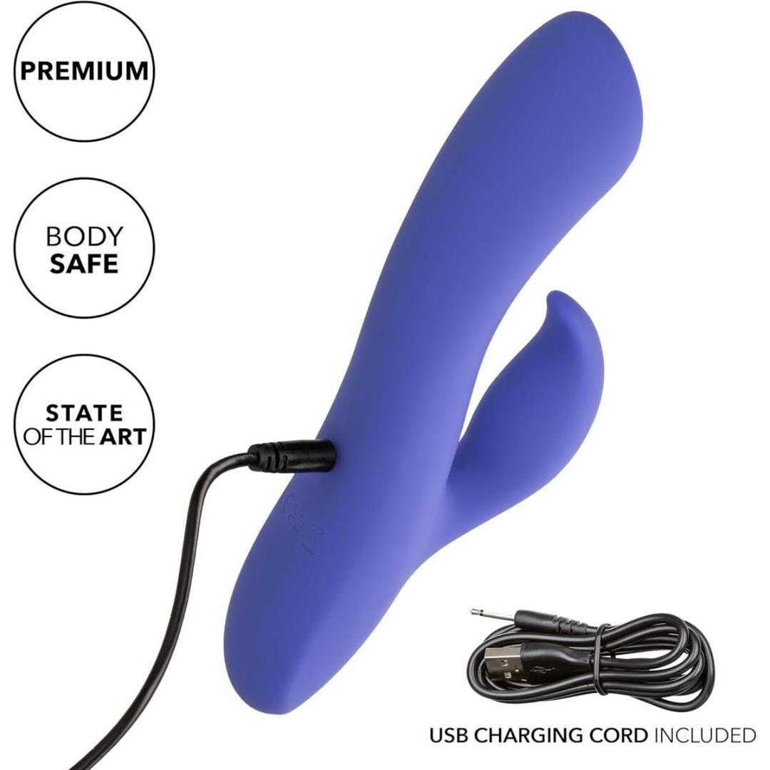 A CalExotics Connect Dual Stimulator in blue, shown with its USB charging cord plugged in and a coiled cable nearby. The image features the text: "Premium," "Body Safe," "State of the Art," and "USB charging cord included.
