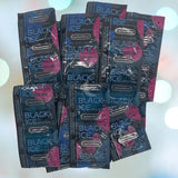 A stack of Caution Wear Black Ice Condoms, featuring black and pink packaging, offers enhanced sensitivity with a silicone-based lubricant, displayed against a vibrant, blurred background.