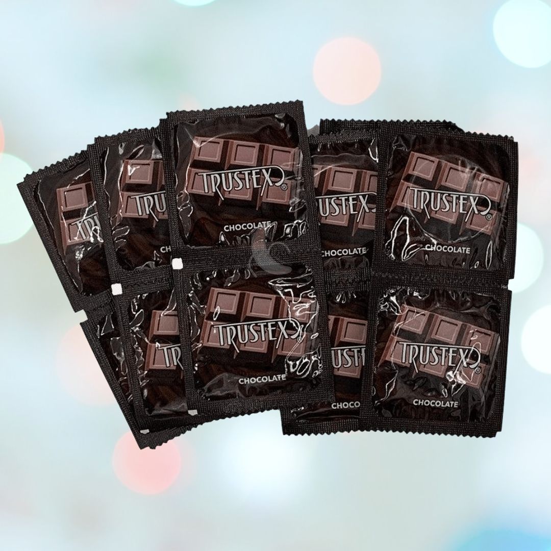 A neat stack of Trustex Chocolate Flavored Condoms 🍫 is arranged meticulously. The black packaging, featuring an image of rich chocolate bars, contrasts beautifully against a softly blurred pastel background.