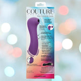 The CalExotics Couture Collection Dual Pleasure Wand, in purple silicone, is shown in its box against a pastel light background. The packaging highlights 10 functions, easy cleaning, and USB charging.