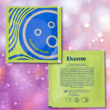 Two square wrappers for Dame Ultra-Thin Vegan Friendly Latex Condoms are displayed—a green one featuring playful circles and the phrase “let’s come together,” and a blue one showing the Dame brand name with product details. Set against a soft pink bokeh backdrop, these ultra-thin condoms are made from natural rubber latex and are fully vegan, offering both comfort and mindful design.