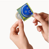 Two hands hold an unwrapped Dame Ultra-Thin Vegan Friendly Latex Condom and its blue and yellow packaging against a white background, highlighting Dame condoms designed for a more natural feeling.
