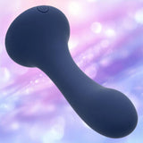The CalExotics Deep Curve Vibrating Probe is a dark blue, curved personal massager with a rounded tip and power button, set against a soft pastel bokeh background in purple and pink tones.