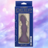 A boxed CalExotics Deep Stud Vibrating Probe in purple, made of body-safe silicone, is shown against a pastel purple and pink blurred background. The packaging displays features and the product name "STUD" at the bottom.