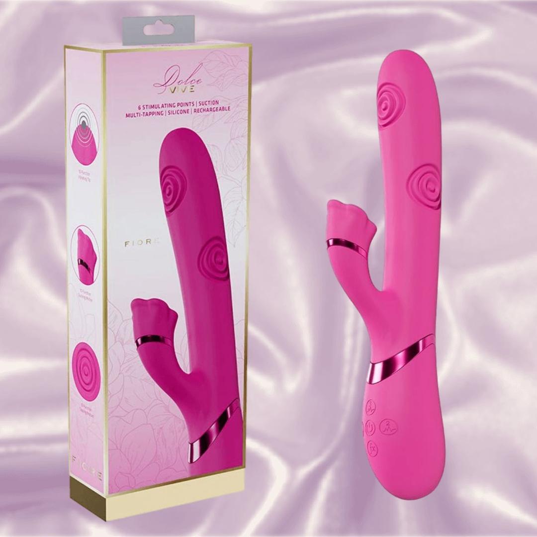 The Dolce Vive Fiore Rechargeable G-Spot Air Wave Vibrating and Tapping Clit by Shots America, featuring a curved pink silicone design with dual stimulation, is shown beside its packaging on a soft, light pink satin background.