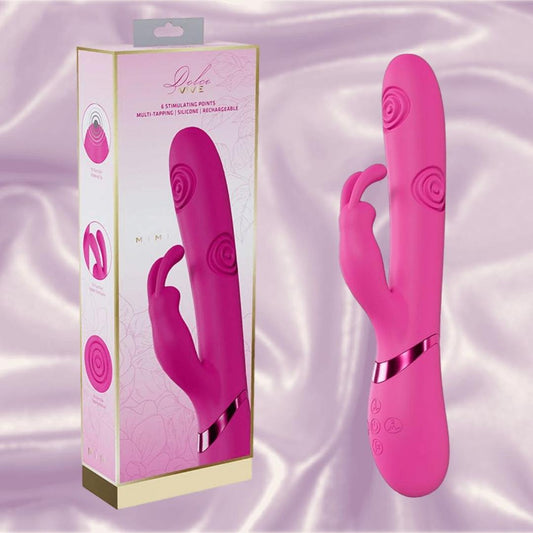 The Dolce Vive Mimi Rechargeable G-Spot Vibrating and Tapping Rabbit-Pink by Shots America features a dual design with textured patterns, shown beside its branded packaging against a silky light purple backdrop. 1080