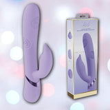 The Dolce Vive Pallina Rechargeable G-Spot Vibrating and Tapping Beads Clit by Shots America, a purple silicone toy with a curved shaft and tapping clitoral stimulator, is displayed beside its branded packaging on a soft pastel bokeh background.