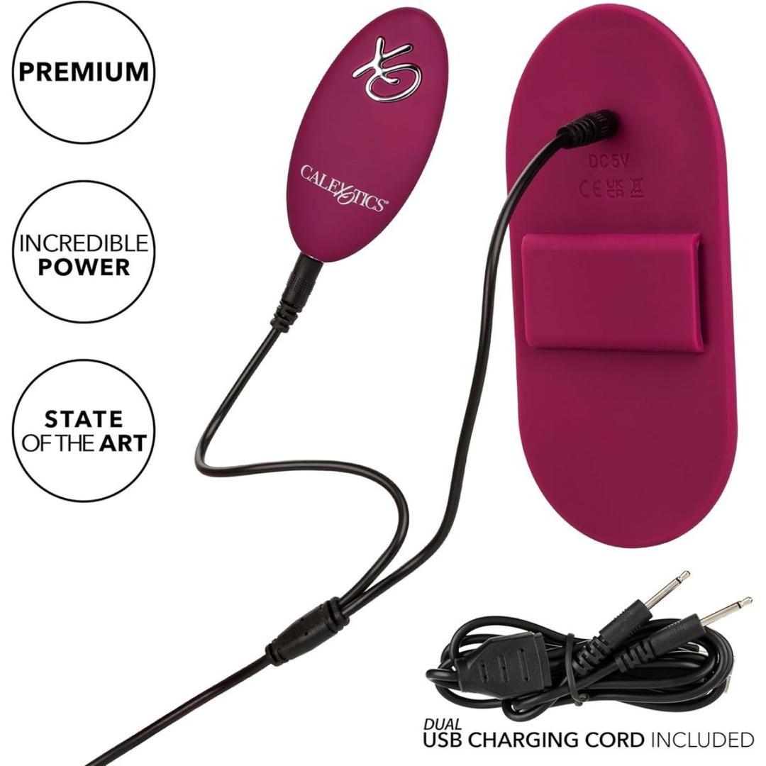 The CalExotics Dual Rider Remote Control Grinder is a magenta massager featuring an attached control pad, dual USB charging cord, and labels: “premium,” “incredible power,” and “state of the art.”.