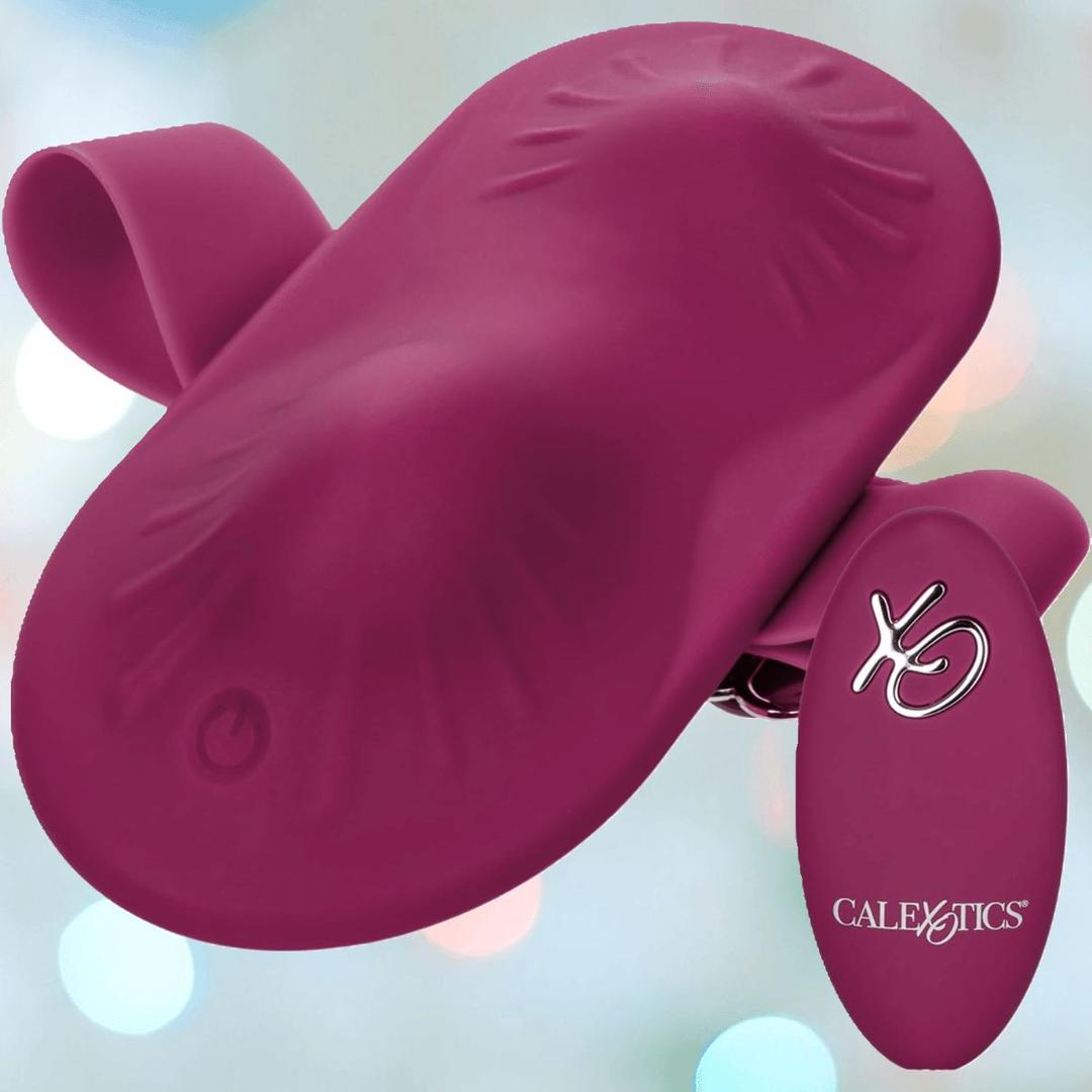 The CalExotics Dual Rider Remote Control Grinder is a maroon silicone wearable vibrator with dual flexible arms and a small remote, displayed on a soft, blurred pastel background.