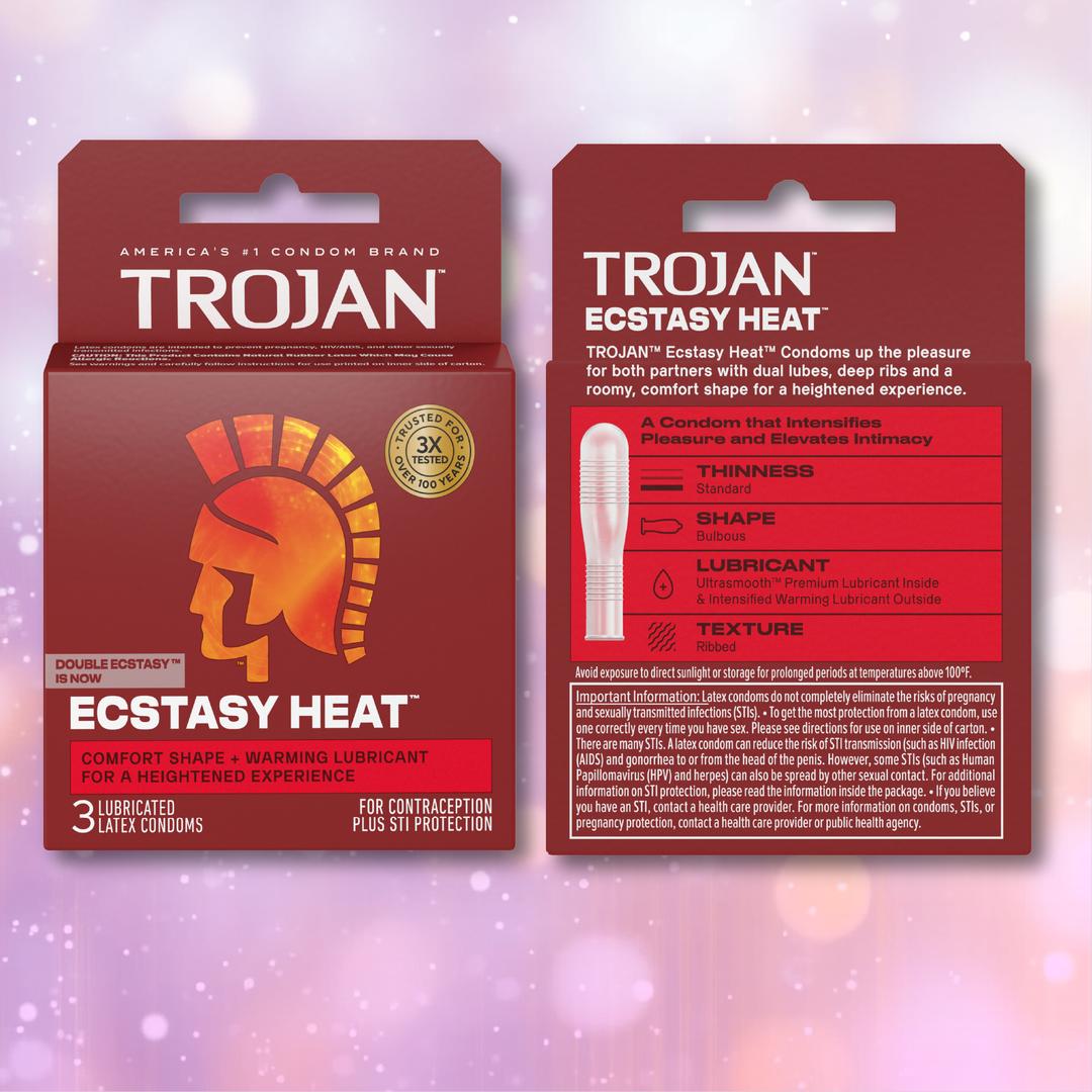 Two boxes of Trojan Double Ecstasy Condoms: Now Ecstasy Heat, displaying vibrant red packaging with the iconic gold Trojan helmet logo. The text emphasizes the comfort fit shape, innovative warming lubricant, ribbed texture, and other key features—all set against a softly blurred pink background.