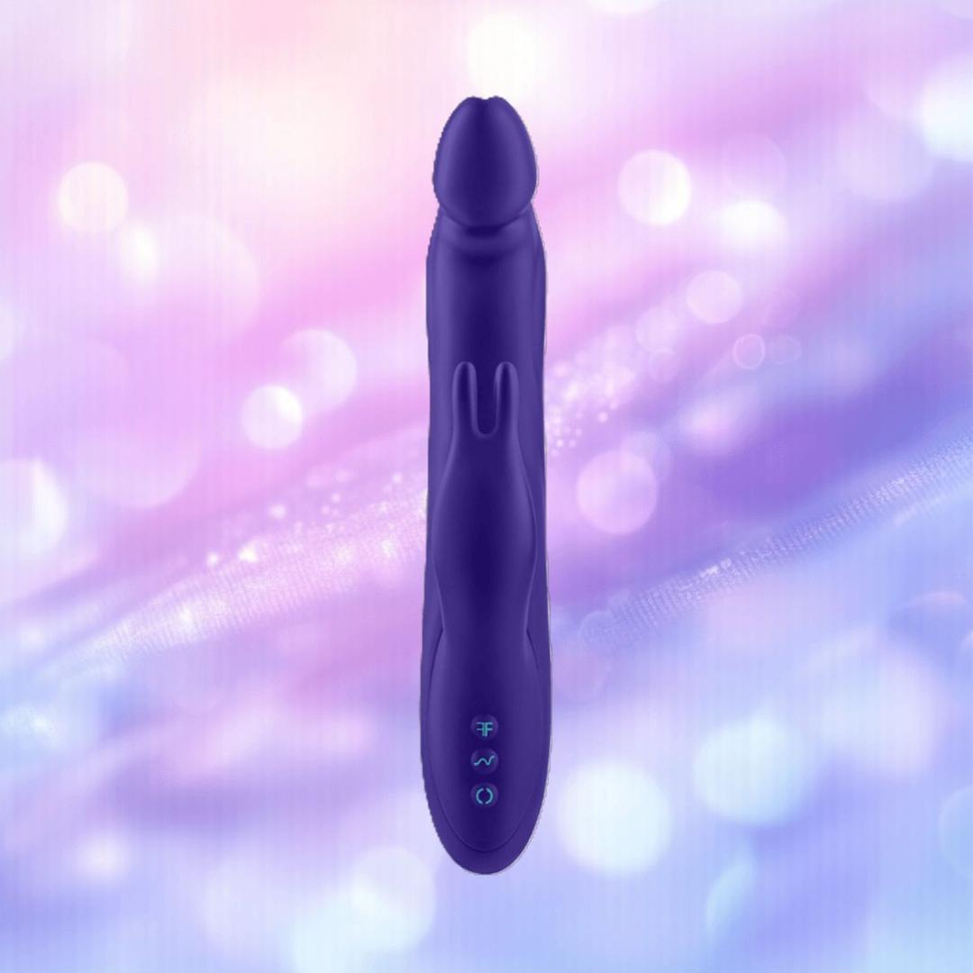 The FemmeFunn Booster Rabbit XL Dark Purple, a waterproof silicone dual-action vibrator by Femme Funn, features a rounded tip and control buttons, shown upright against a pastel purple and pink bokeh background.