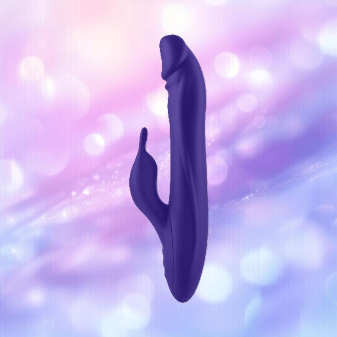 The FemmeFunn Booster Rabbit XL Dark Purple by Femme Funn is a dark purple, curved dual-action vibrator with a smaller extension, crafted from waterproof silicone and set against a soft, blurred background with pink, purple, and blue bokeh lights.