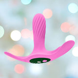 The Femme Funn Ossia Wearable Bullet Vibrator - Pink, an ergonomically designed remote-controlled vibrator with a curved shape and textured surface, is displayed against a soft, multi-colored bokeh background. The vibrator features two round buttons on a dark green base and offers 10 vibration modes for personalized pleasure.