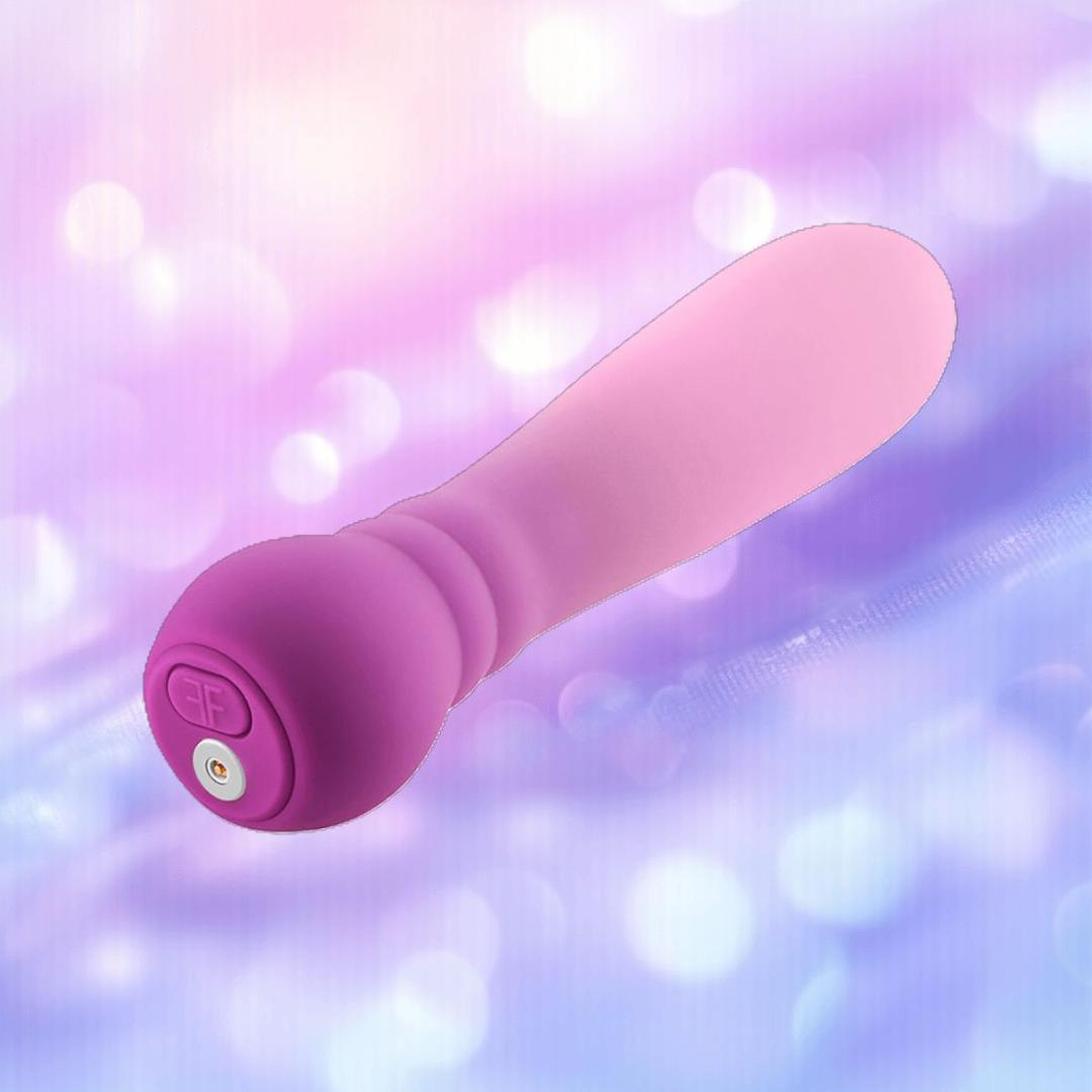 The Femme Funn Anniversary Ultra Bullet Orchid, a pink and purple silicone vibrator by Femme Funn, is featured against a soft purple and blue bokeh background—ideal as a compact, travel-friendly pleasure toy.