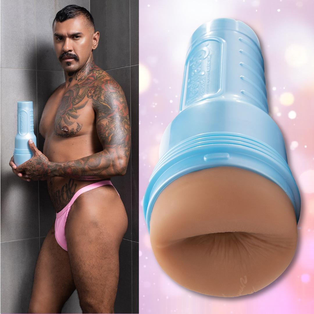 A tattooed man with a mustache, wearing pink underwear, stands in a shower holding the Fleshlight Fleshjack Boys Boomer Banks Realistic Male Masturbator Cake Butt. Beside him is a close-up of the product against a softly lit pink background.