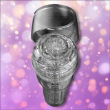 A transparent Fleshlight GO Torque Portable Stroker Male Masturbation Toy by Fleshlight, featuring a detailed interior and open lid, is displayed against a purple background with light bokeh effects.