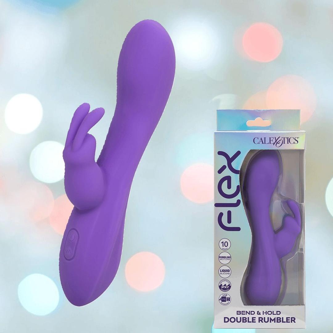 The CalExotics Flex Bend & Hold Double Rumbler Rabbit Vibrator, featuring a purple curved silicone shaft and two bunny ear-shaped tips, is displayed beside its packaging against a soft pastel background.