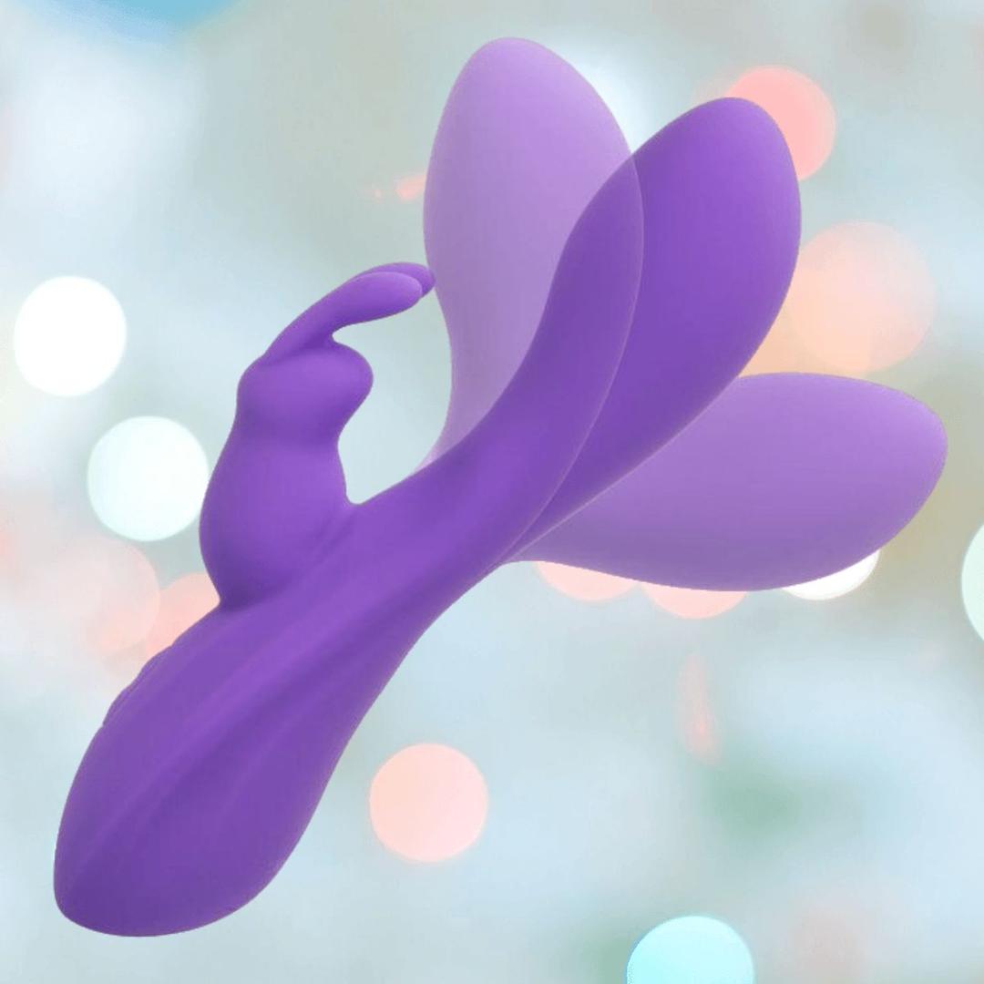 The CalExotics Flex Bend & Hold Double Rumbler Rabbit Vibrator—a purple silicone vibe with curved extensions and a butterfly-inspired design—provides dual stimulation for heightened pleasure, set against a soft pastel bokeh background.